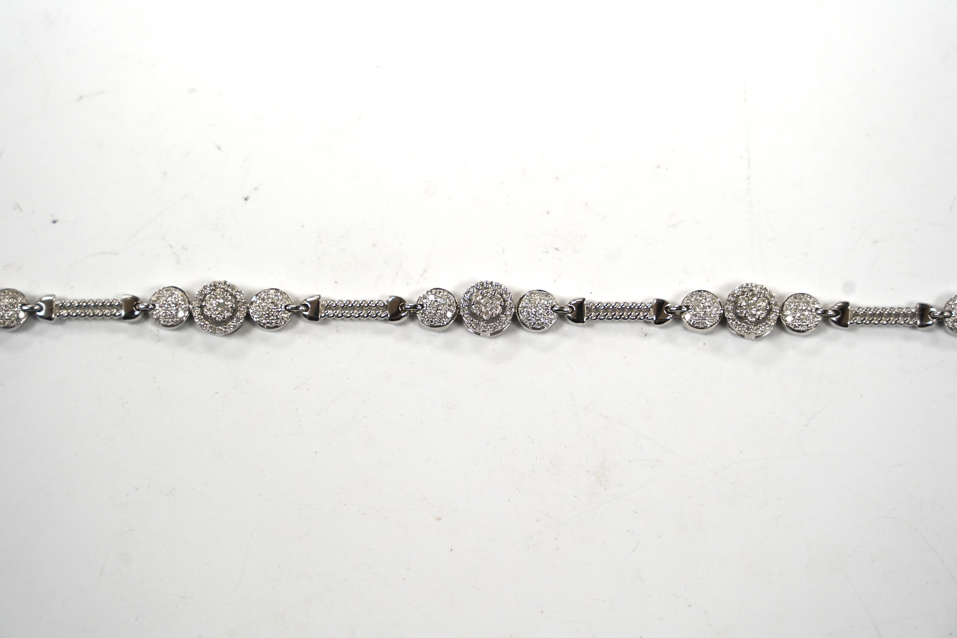 A modern 14k white metal and diamond cluster set line bracelet, the total diamond weight approximately 2.00ct, 16.5cm, gross weight 11.1 grams.
